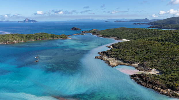 Aerial view of Chance Bay featuring turquoise waters rocky coastline and lush green vegetation in the Whitsundays Queensland Australia. Aerial view of Chance Bay featuring turquoise waters rocky coastline and lush green vegetation in the Whitsundays Queensland Australia.
