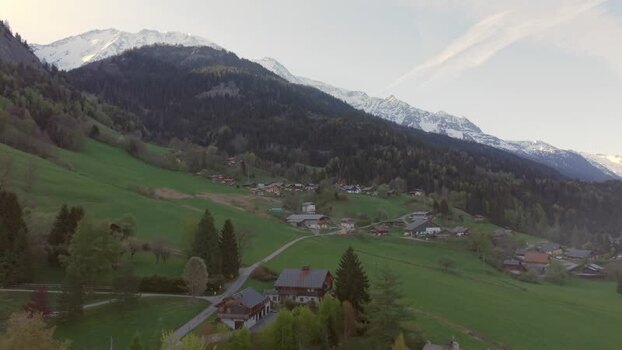 FPV aerial view of alpine village and snow capped mountains France.