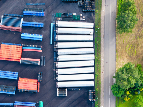 Aerial view of a manufacturing facility yard featuring stacks of high efficiency polymer pipes and industrial components arranged in organized rows on asphalt Jelgava Latvia. Aerial view of a manufacturing facility yard featuring stacks of high efficiency polymer pipes and industrial components arranged in organized rows on asphalt Jelgava Latvia.