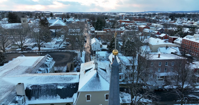 Aerial view of the historic town of Lititz covered in snow featuring a church steeple residential rooftops and quiet streets in Lititz Pennsylvania United States.