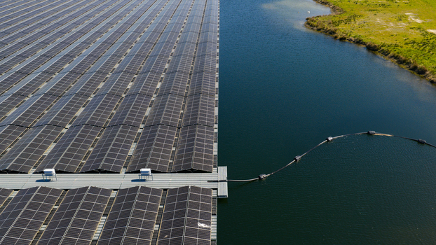 Aerial view of a large floating solar farm with rows of photovoltaic panels on a calm lake next to a grassy shoreline Zwolle Overijssel Netherlands. Aerial view of a large floating solar farm with rows of photovoltaic panels on a calm lake next to a grassy shoreline Zwolle Overijssel Netherlands.