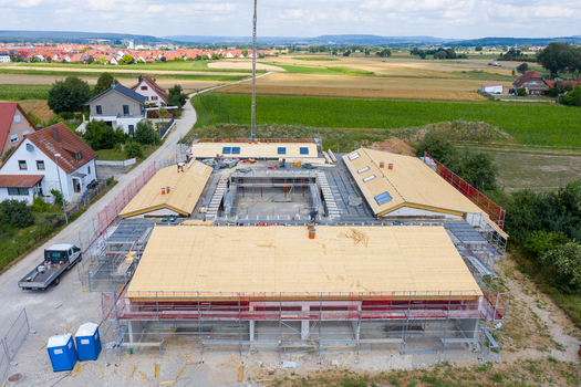 Igensdorf Germany 11 May 2024 Aerial view of a large building construction site with workers and scaffolding surrounded by fields and houses. Igensdorf Germany 11 May 2024 Aerial view of a large building construction site with workers and scaffolding surrounded by fields and houses.