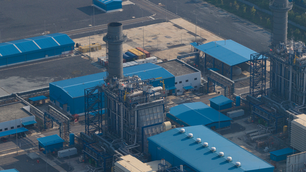 Aerial view of a large industrial power plant featuring tall chimneys and blue roofed warehouses in Map Yang Phon Rayong Thailand. Aerial view of a large industrial power plant featuring tall chimneys and blue roofed warehouses in Map Yang Phon Rayong Thailand.