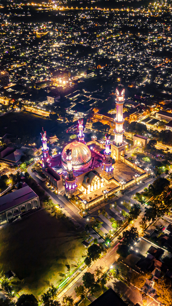 Aerial view of the illuminated Islamic Center NTB Hubbul Wathan Great Mosque at night with its glowing dome and minarets in Kecamatan Selaparang Nusa Tenggara Barat Indonesia. Aerial view of the illuminated Islamic Center NTB Hubbul Wathan Great Mosque at night with its glowing dome and minarets in Kecamatan Selaparang Nusa Tenggara Barat Indonesia.