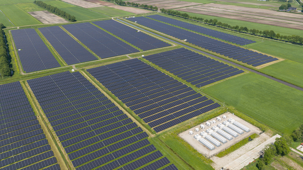 Aerial view of a large solar farm with rows of photovoltaic panels and battery storage units surrounded by green agricultural fields in Wanneperveen Overijssel Netherlands. Aerial view of a large solar farm with rows of photovoltaic panels and battery storage units surrounded by green agricultural fields in Wanneperveen Overijssel Netherlands.