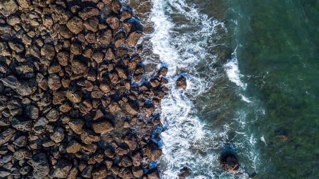 Aerial view of rocky coastline with waves crashing against the shore in Bajawa Nusa Tenggara Timur Indonesia. Aerial view of rocky coastline with waves crashing against the shore in Bajawa Nusa Tenggara Timur Indonesia.