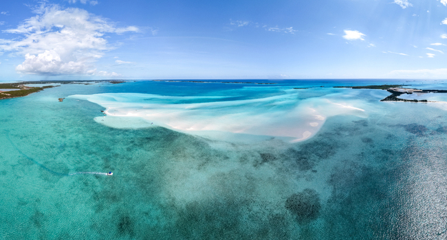 Aerial view of the Man O War Cay Sandbar surrounded by turquoise waters and white sand under a clear blue sky in Rolletown Exuma The Bahamas. Aerial view of the Man O War Cay Sandbar surrounded by turquoise waters and white sand under a clear blue sky in Rolletown Exuma The Bahamas.