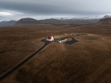Aerial view of Ingjaldsholl Church with its distinctive red roof standing alone in the vast rugged landscape under a cloudy sky in Hellissandur Snaefellsbaer Iceland. Aerial view of Ingjaldsholl Church with its distinctive red roof standing alone in the vast rugged landscape under a cloudy sky in Hellissandur Snaefellsbaer Iceland.