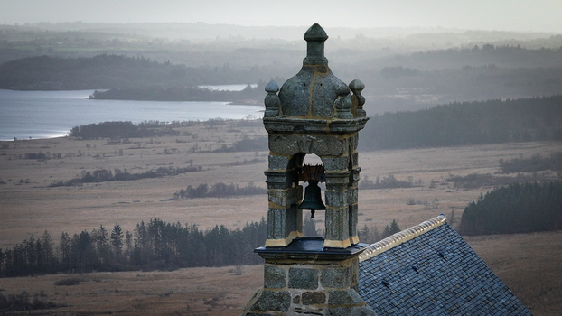 Aerial view of the stone bell tower of Mont Saint Michel de Brasparts overlooking misty hills and valleys of the Armorique Regional Natural Park in Saint Rivoal Bretagne France. Aerial view of the stone bell tower of Mont Saint Michel de Brasparts overlooking misty hills and valleys of the Armorique Regional Natural Park in Saint Rivoal Bretagne France.