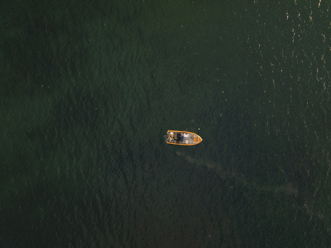 Aerial view of a small orange fishing boat floating on the calm dark sea near the historic town of Nessebar Burgas Bulgaria. Aerial view of a small orange fishing boat floating on the calm dark sea near the historic town of Nessebar Burgas Bulgaria.
