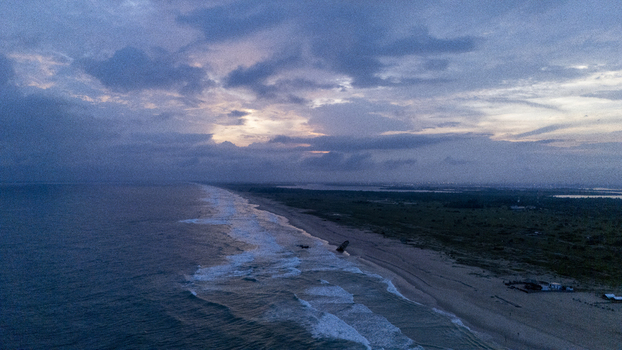 Aerial view of Tarkwa Bay Beach featuring waves crashing on the sandy shoreline under a dramatic cloudy sky at dusk in Lagos Lagos Nigeria. Aerial view of Tarkwa Bay Beach featuring waves crashing on the sandy shoreline under a dramatic cloudy sky at dusk in Lagos Lagos Nigeria.