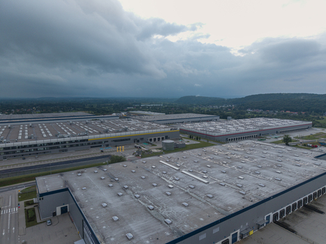 Aerial view of a large logistics hub with expansive warehouse buildings featuring flat roofs and loading docks under a cloudy sky in Skawina Lesser Poland Voivode Poland. Aerial view of a large logistics hub with expansive warehouse buildings featuring flat roofs and loading docks under a cloudy sky in Skawina Lesser Poland Voivode Poland.