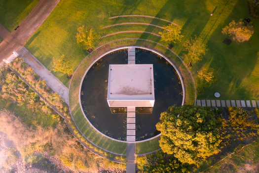 Aerial view of a modern square pavilion centered in a circular pond surrounded by lush green lawns and trees during golden hour in Cape Town Western Cape South Africa. Aerial view of a modern square pavilion centered in a circular pond surrounded by lush green lawns and trees during golden hour in Cape Town Western Cape South Africa.