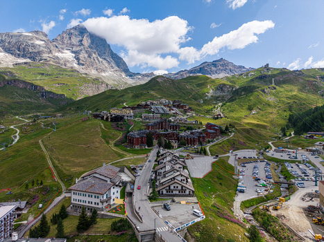 Aerial view of the alpine village of Breuil Cervinia with the Matterhorn peak in the background surrounded by lush green slopes and mountain architecture in Breuil Cervinia Aosta Valley Italy. Aerial view of the alpine village of Breuil Cervinia with the Matterhorn peak in the background surrounded by lush green slopes and mountain architecture in Breuil Cervinia Aosta Valley Italy.