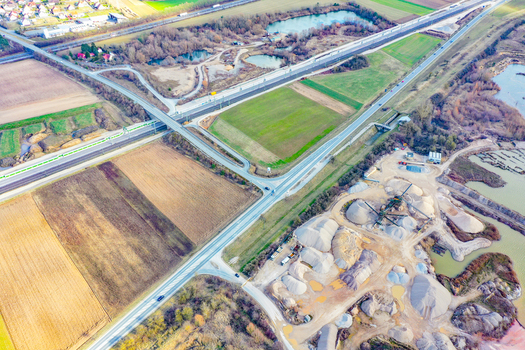 Aerial view of a highway intersection and railway line with a passing train near a gravel quarry and agricultural fields in Forchheim Bavaria Germany. Aerial view of a highway intersection and railway line with a passing train near a gravel quarry and agricultural fields in Forchheim Bavaria Germany.