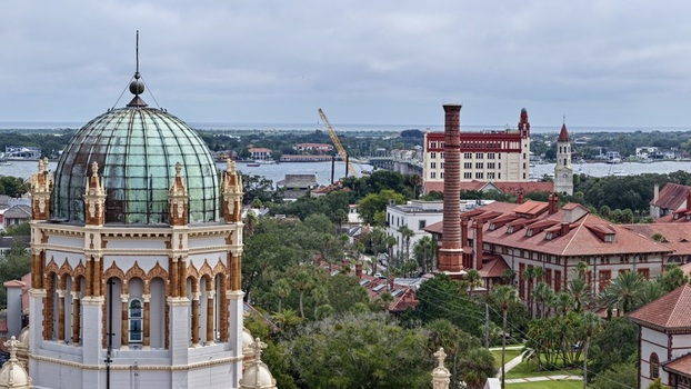 Aerial view of Memorial Presbyterian Church with its green dome historic buildings with red tile roofs a tall brick chimney and a bridge in St. Augustine Florida United States.