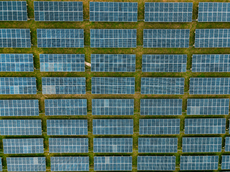Aerial view of rows of photovoltaic solar panels arranged in a grid pattern over a grassy field in Ogun State Nigeria.