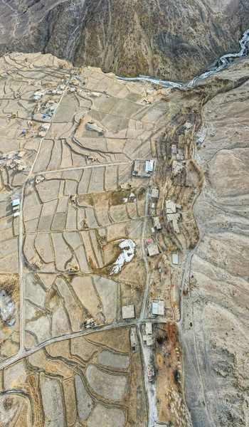 Aerial view of terraced fields meeting the rugged mountains bisected by a winding river a tapestry of earth tones under a vast sky Hunza Nagar Gilgit Pakistan. Aerial view of terraced fields meeting the rugged mountains bisected by a winding river a tapestry of earth tones under a vast sky Hunza Nagar Gilgit Pakistan.