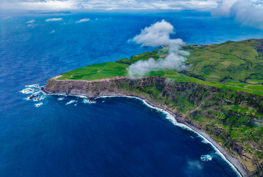 Aerial view of the rugged coastline where the dark cliffs meet the vibrant green landscapes Flores A&ccedil;ores Portugal.