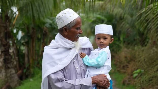 View of an elderly man holding a young boy in Bogura Bangladesh. View of an elderly man holding a young boy in Bogura Bangladesh.