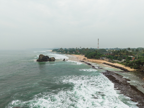 Aerial view of the scenic coastline featuring rocky outcrops sandy beaches and lush palm trees along the shore in Koggala Southern Province Sri Lanka. Aerial view of the scenic coastline featuring rocky outcrops sandy beaches and lush palm trees along the shore in Koggala Southern Province Sri Lanka.