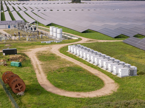 Aerial view of the BESS battery energy storage system with rows of white containers and electrical infrastructure situated next to a vast solar farm in Poland. Aerial view of the BESS battery energy storage system with rows of white containers and electrical infrastructure situated next to a vast solar farm in Poland.