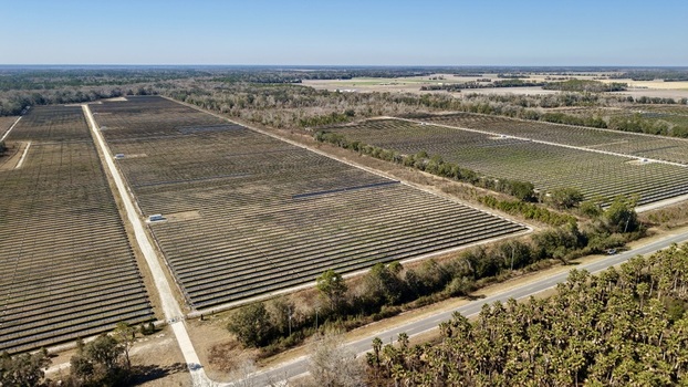 Aerial view of a vast solar farm shimmering under the bright sun bordered by dark green trees Elkton Florida United States. Aerial view of a vast solar farm shimmering under the bright sun bordered by dark green trees Elkton Florida United States.