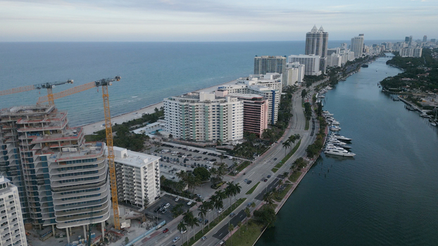Aerial view of the Miami Beach coastline featuring high rise residential buildings a construction site with tall cranes and a waterway filled with yachts in Miami Beach Florida United States. Aerial view of the Miami Beach coastline featuring high rise residential buildings a construction site with tall cranes and a waterway filled with yachts in Miami Beach Florida United States.