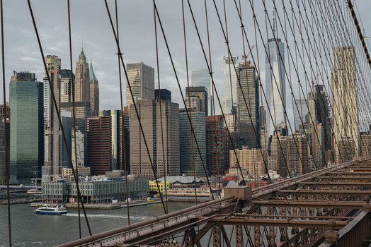 View of the Brooklyn Bridge with steel suspension cables in the foreground and the New York City skyline including One World Trade Center New York New York United States.