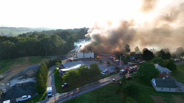 Rapho Township Pennsylvania United States 05 July 2023 Aerial view of a large building fire with thick smoke emergency vehicles and firefighters working to extinguish the flames.