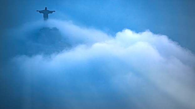 View of Christ the Redeemer statue emerging from thick white clouds under a deep blue sky in Rio de Janeiro Rio de Janeiro Brazil.