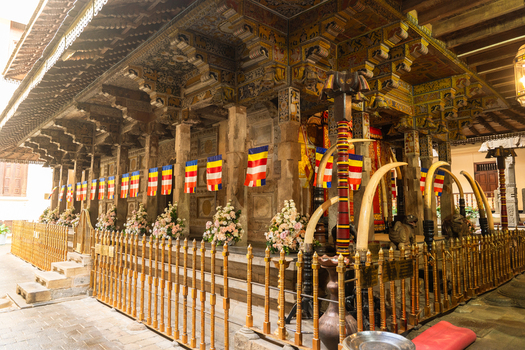 View of the Temple of the Sacred Tooth Relic with intricate wood carvings Buddhist flags and elephant tusks in Kandy Central Province Sri Lanka. View of the Temple of the Sacred Tooth Relic with intricate wood carvings Buddhist flags and elephant tusks in Kandy Central Province Sri Lanka.