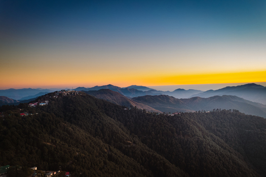 Aerial view of the hill station nestled on mountain ridges under a vibrant sunset sky with lush green slopes and distant peaks Chakrata Uttarakhand India. Aerial view of the hill station nestled on mountain ridges under a vibrant sunset sky with lush green slopes and distant peaks Chakrata Uttarakhand India.