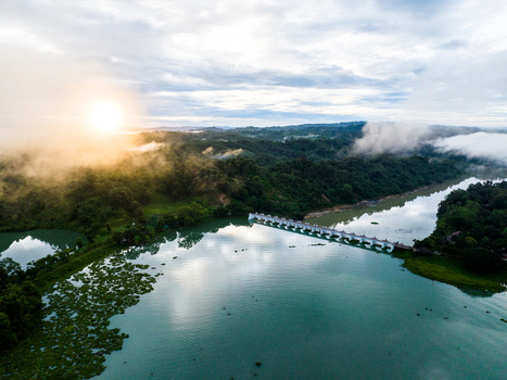 Aerial view of the Kaptai Lake bridge surrounded by lush green hills and mist during a golden sunset in Rangamati Chittagong Division Bangladesh. Aerial view of the Kaptai Lake bridge surrounded by lush green hills and mist during a golden sunset in Rangamati Chittagong Division Bangladesh.