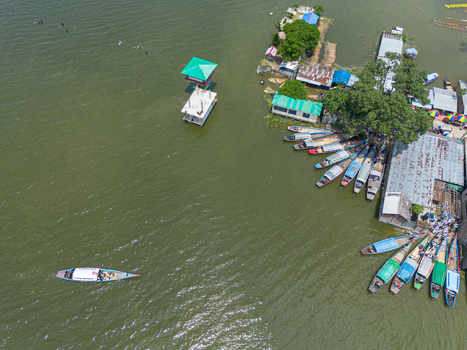 Aerial view of Patul with small boats docked at the pier and a boat navigating the water in Natore District Rajshahi Division Bangladesh.