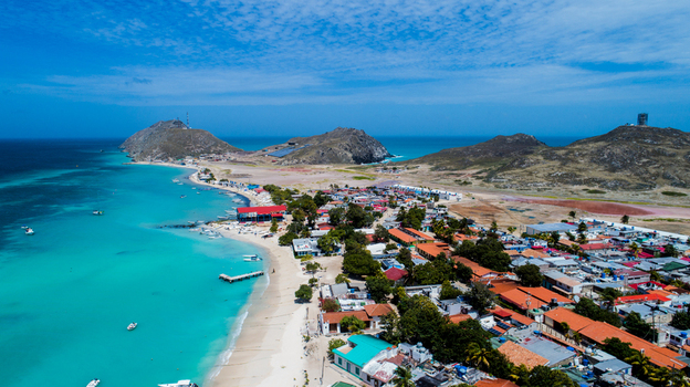Aerial view of Los Roques archipelago featuring turquoise waters a sandy beach and a coastal village with colorful rooftops in Los Roques Dependencias Federale Venezuela. Aerial view of Los Roques archipelago featuring turquoise waters a sandy beach and a coastal village with colorful rooftops in Los Roques Dependencias Federale Venezuela.