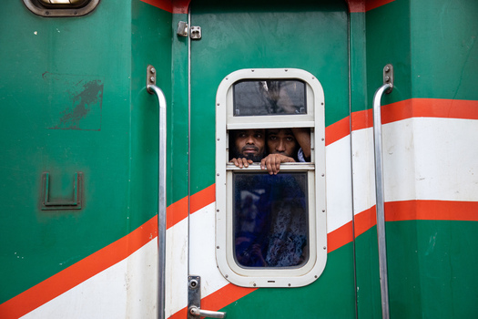 Dhaka Bangladesh 15 June 2018 View of two men looking out from a small window of a green train carriage at Airport Railway Station. Dhaka Bangladesh 15 June 2018 View of two men looking out from a small window of a green train carriage at Airport Railway Station.