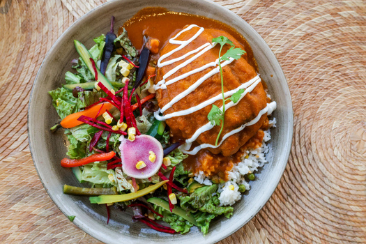 View of a bowl of meat in red sauce with cream served with fresh salad of lettuce radish corn and peppers over white rice in Cabo San Lucas Baja California Sur Mexico.