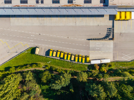 Aerial view of Logistikzentrum Allhaming featuring a row of yellow delivery vans parked in the warehouse yard surrounded by green trees in Allhaming Oberosterreich Austria. Aerial view of Logistikzentrum Allhaming featuring a row of yellow delivery vans parked in the warehouse yard surrounded by green trees in Allhaming Oberosterreich Austria.