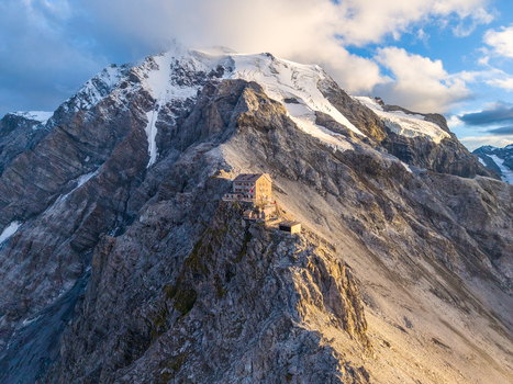 Aerial view of the Payer Hut perched on the rocky ridge of Ortler Mountain with snow capped peaks and dramatic alpine terrain in Stilfs Trentino Alto Adige Italy. Aerial view of the Payer Hut perched on the rocky ridge of Ortler Mountain with snow capped peaks and dramatic alpine terrain in Stilfs Trentino Alto Adige Italy.