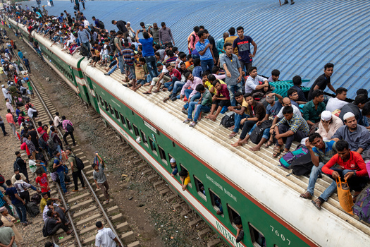 Dhaka Bangladesh 14 June 2018 View of a crowded train at Airport Railway Station with many passengers sitting on the roof and standing on the tracks during a busy travel period. Dhaka Bangladesh 14 June 2018 View of a crowded train at Airport Railway Station with many passengers sitting on the roof and standing on the tracks during a busy travel period.