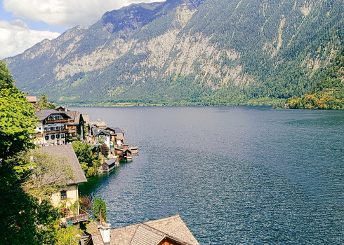 View of Hallstatt village with traditional houses nestled along the shore of Lake Hallstatt against a backdrop of towering mountains in Hallstatt Upper Austria Austria. View of Hallstatt village with traditional houses nestled along the shore of Lake Hallstatt against a backdrop of towering mountains in Hallstatt Upper Austria Austria.