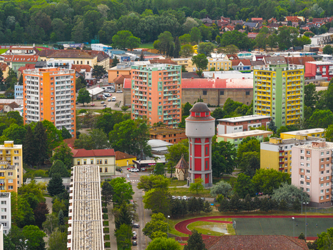 Aerial view of a residential area featuring a distinctive red water tower colorful apartment blocks green trees and a sports track in Breclav South Moravian Region Czechia.