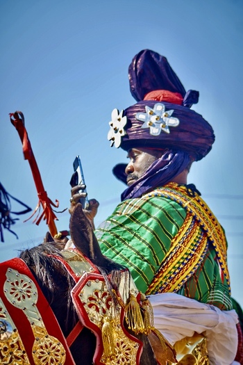 Zaria City Nigeria 21 March 2026 View of a regal figure in vibrant green and gold attire with a dark flower adorned turban riding a richly decorated horse. Zaria City Nigeria 21 March 2026 View of a regal figure in vibrant green and gold attire with a dark flower adorned turban riding a richly decorated horse.