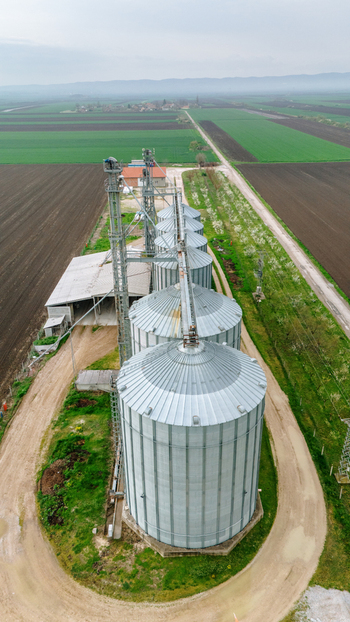 Aerial view of gleaming metal grain silos stand in contrast to the tilled fields a testament to agricultural industry Sremska Mitrovica Vojvodina Serbia. Aerial view of gleaming metal grain silos stand in contrast to the tilled fields a testament to agricultural industry Sremska Mitrovica Vojvodina Serbia.