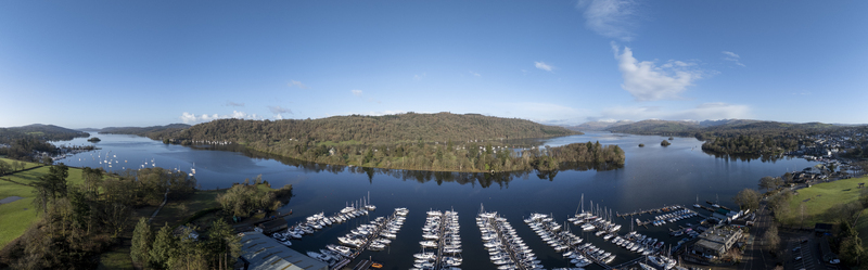 Aerial view of boats nestled in the marina s embrace reflecting the sky s hue with the backdrop of the lush fells Bowness on Windermere England United Kingdom. Aerial view of boats nestled in the marina s embrace reflecting the sky s hue with the backdrop of the lush fells Bowness on Windermere England United Kingdom.