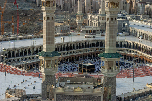 Aerial view of Masjid al Haram featuring the Kaaba surrounded by pilgrims tall minarets and expansive marble courtyards in Makkah Makkah Province Saudi Arabia. Aerial view of Masjid al Haram featuring the Kaaba surrounded by pilgrims tall minarets and expansive marble courtyards in Makkah Makkah Province Saudi Arabia.