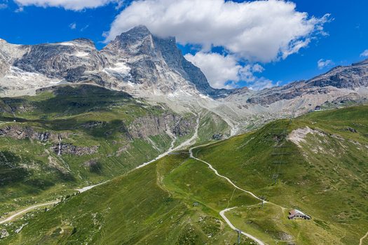Aerial view of the Matterhorn mountain peak rising above the green alpine slopes and hiking trails of Breuil Cervinia Aosta Valley Italy. Aerial view of the Matterhorn mountain peak rising above the green alpine slopes and hiking trails of Breuil Cervinia Aosta Valley Italy.