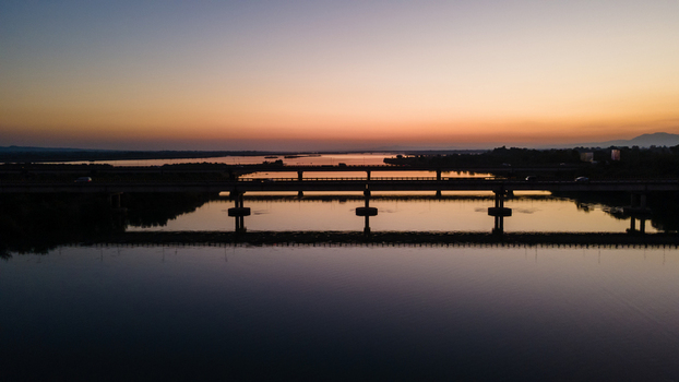Aerial view of the Jhelum River bridge at sunset with silhouettes of vehicles and calm water reflections Jhelum Punjab Pakistan. Aerial view of the Jhelum River bridge at sunset with silhouettes of vehicles and calm water reflections Jhelum Punjab Pakistan.