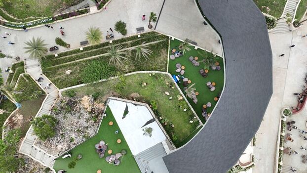 Aerial view of Obelix Sea View featuring a modern curved roof structure landscaped green areas outdoor seating and pathways in Kecamatan Purwosari Daerah Istimewa Yogya Indonesia. Aerial view of Obelix Sea View featuring a modern curved roof structure landscaped green areas outdoor seating and pathways in Kecamatan Purwosari Daerah Istimewa Yogya Indonesia.